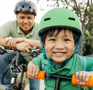 parent and child riding bikes. close up shot of child's smiling face